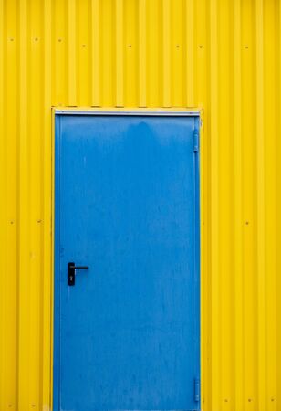 Blue close metalic door on a yellow wall. Minimal abstract photographの写真素材