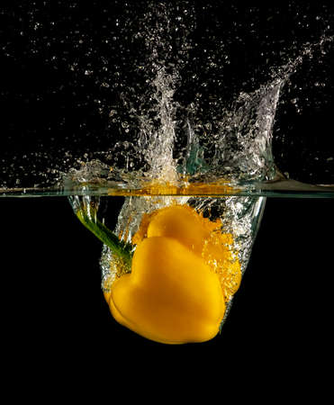 Yellow fresh and healthy bell pepper dropped and slashing on waterの写真素材