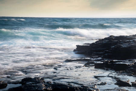 Splashing stormy windy sea waves on a rocky seashore