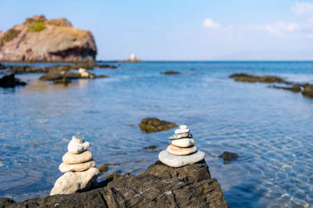 Pyramid of balancing white pebbles, on the rock of a rocky beachの写真素材