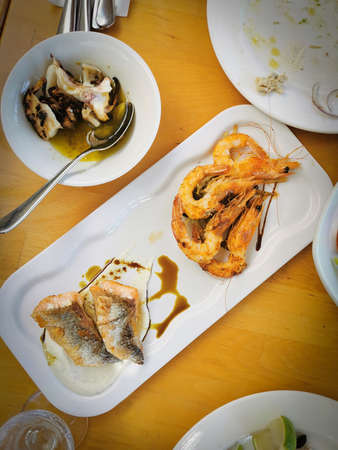 Slices of fresh healthy fish with shrimps, salmon steak a octopus on a plate on a tableの写真素材