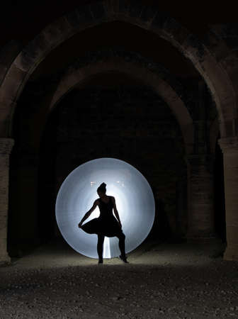 Young woman dancing below an old stoned column  with circle of painting light behind. Lightpainting photographyの写真素材