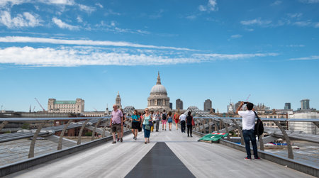 People walking on the millennium bridge and Saint Paul Cathedral in London UKのeditorial素材