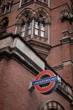 St Prancras london underground station and red underground sign on the building against cloudy skyのeditorial素材