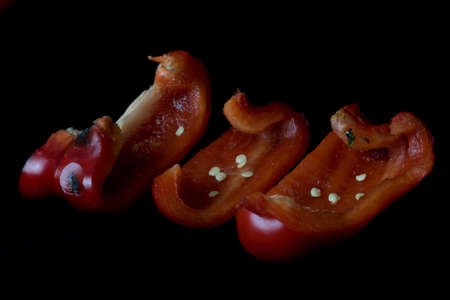 Red moldy pepper on a black background