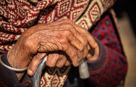 Close up of the crossed wrinkle hands of an elder grandmother nepalese woman.の写真素材