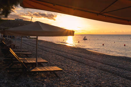 Beach umbrellas and relaxing chairs at sea at sunrise. Empty beach Pissouri Cyprus
