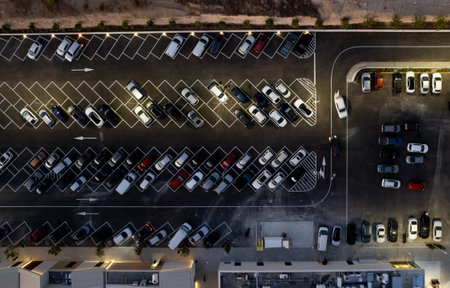 Drone aerial view of parking lots with cars at night. Crowded shopping mall car park.