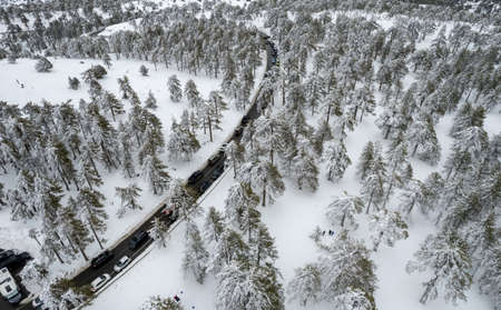 Drone aerial scenery of highway road crossing the snowy mountain forest landscape in winteの写真素材