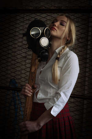 Woman with toxic protective mask holding axe in an underground warehouseの写真素材