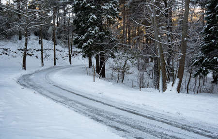 Icy slippery dangerous road in winter in the forest. Snowy mountains snowstorm.