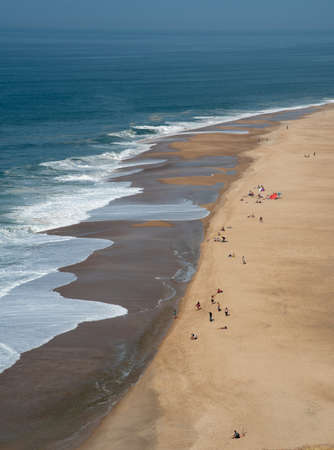 Tourist people relaxing and sunbathing a sandy tropical beach. Nazare Portugalの写真素材