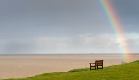 Rainbow over the ocean and wooden bench on the coast for relaxing. Atlantic ocean englandの写真素材
