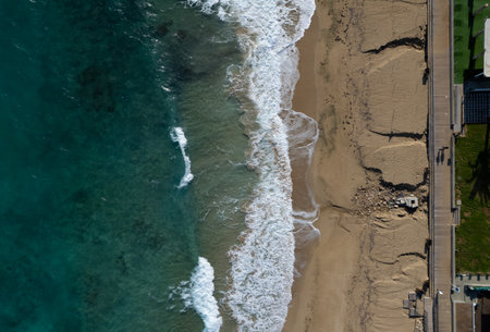 Aerial view of ocean waves breaking on a sandy beach. Beach erosion after coastal flooding.
