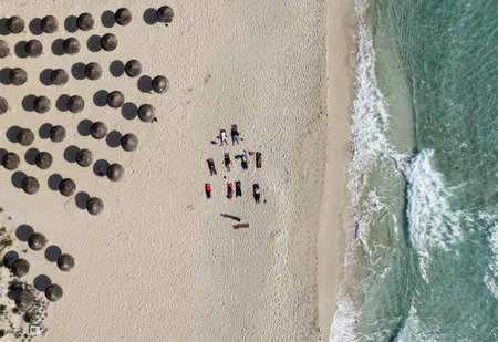 Group of people doing yoga at the beach. Exercising outdoor. Nissi beach Agia Napa Cyprusのeditorial素材