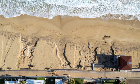 Aerial view of ocean waves breaking on a sandy beach. Beach erosion after coastal flooding.の写真素材