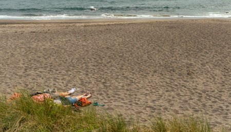 Unrecognized people relaxing on a sandy beach. Atlantic ocean Ireland Europeの写真素材