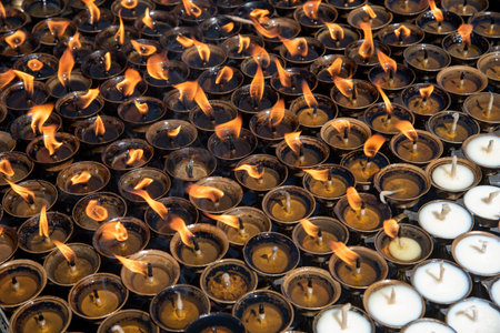 Oil religious candles glowing with orange flames on a hindu temple. Symbols of faith and religion and for wishes and prayersの写真素材