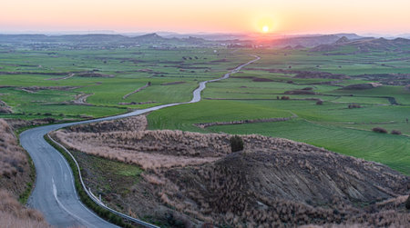 Empty curvy asphalt rural road through farmland filed at sunrise. New day outdoor natureの写真素材