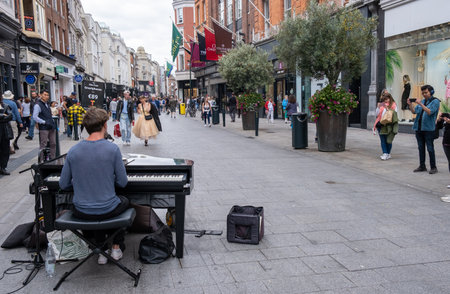 Young pianist street musician playing piano at grafton sopping street in Dublin in ireland with...