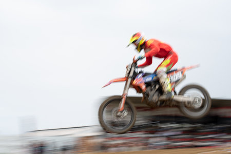 Unrecognized athlete riding a sports motorbike jumping on the air on a motocross race. Fast speed extreme sportの写真素材