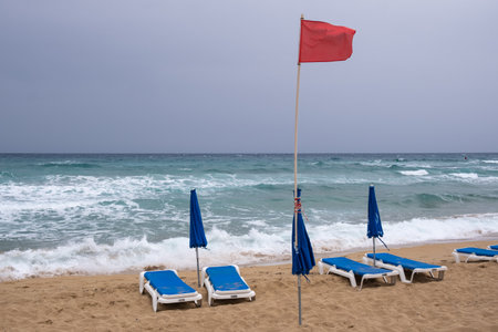Red flag on the stormy tropical sandy beach. Dangerous for swimming.
