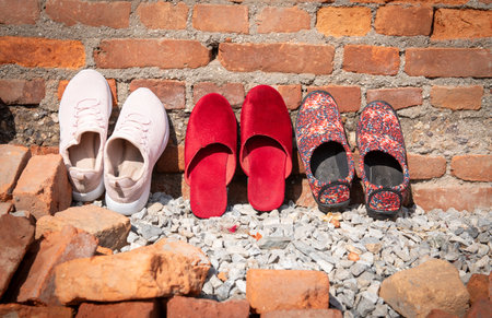 Pair of sneaker shoe slippers and athletic shoes outside a house