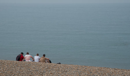 Unrecognized people sitting and relaxing on the beach in the oceanの写真素材