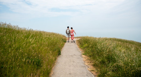Unrecognized couple holding hands walking outdoors on nature