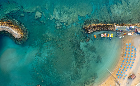 Drone aerial of tropical sandy beach. Beach umbrellas people swimming and relaxing. Summer vacationsの写真素材