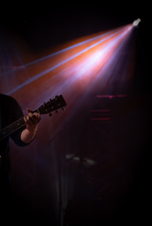 Musician playing guitar on stage under spot light.の写真素材