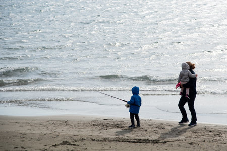 Family with mother and young children walking in the sandy coast. Happy family vacationsの写真素材