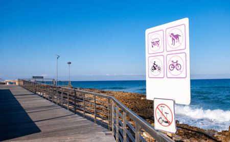 Coastal public wooden footpath. Signpost with forbidden icons on the path . Blue sky copy spaceの写真素材