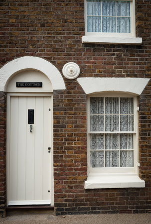 Traditional british village houses exteriors with closed white door and windowの写真素材