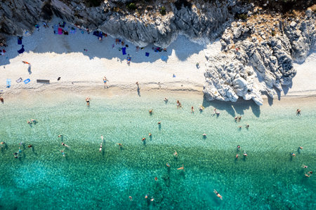 Tourists swimming in crystal clear water of tropical beach. Drone aerial viewの写真素材
