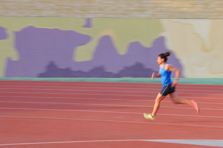 Young female athlete running on track with motion blurの写真素材