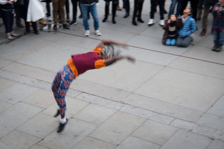 Street performer doing backflip for crowd in cityの写真素材