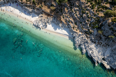 Tourists enjoying summer sunbathing and swimming on secluded beach drone aerial viewの写真素材