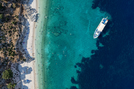 Drone Aerial view of tourists enjoying summer on a Greek isolated tropical beach with turquoise water.の写真素材