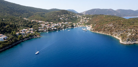 Sailboat sailing on deep blue sea near greek island harbor