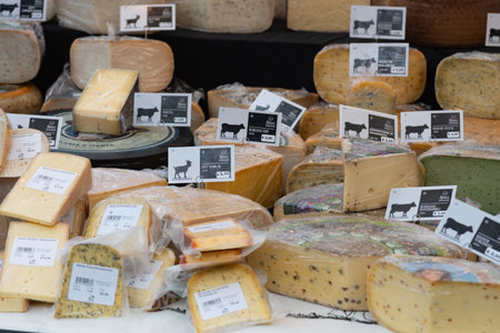 Amsterdam, Netherlands, February 12 2025: Different cheese wedges and pieces are neatly arranged on a market stall, each with a price tag indicating its type and costのeditorial素材