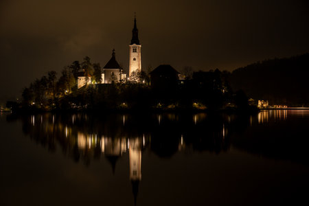 Assumption of mary pilgrimage church on bled island reflecting on lake bled at night. Slovenia, Europeの写真素材