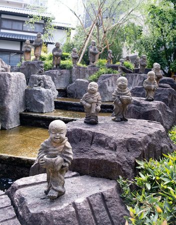 Kyoto, Japan, April 23 2025: Small stone monk statues line a rocky pathway beside a tranquil stream in a lush garden. The setting offers a sense of calm and tranquility amid nature.のeditorial素材