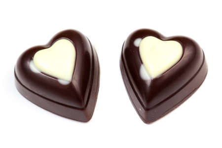 Two chocolates in form of heart on white backgroundの写真素材