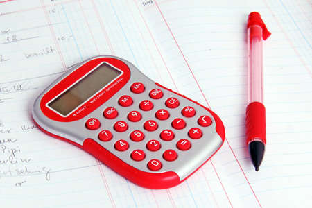 Red calculator on a notebook and red pencil