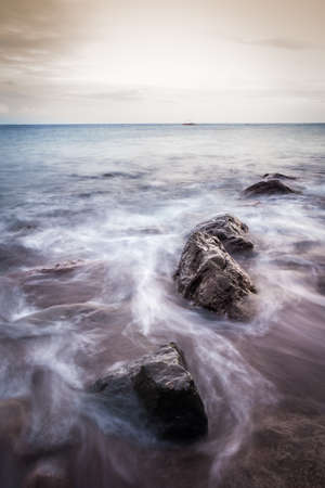 Rocks and flowing waves along the shorelineの写真素材