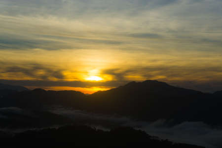 Scenic view of a sunrise over foggy mountain rangeの写真素材