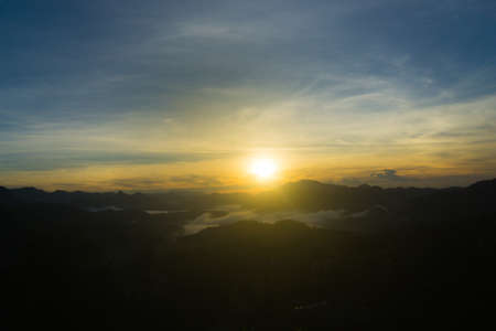 Scenic view of a sunrise over foggy mountain rangeの写真素材