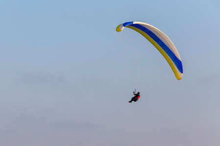 Paraglider flying over the sea coast in blue sky backgroundの写真素材