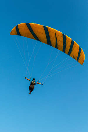 Paraglider flying over the sea coast in blue sky backgroundの写真素材